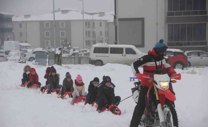 Erzincan’da karla kaplanan boş arazide toplanan çocuklar, kros motorunun arkasına
